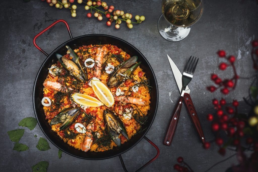 Paella de arroz servida en su paella con la capa de socarrat en el fondo